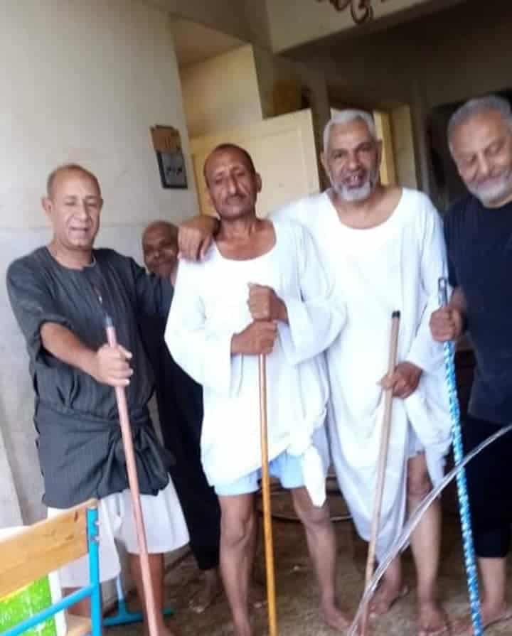 أشخاص ما بين معلمين ومسؤولين، وهم يقومون بتنظيف المدرسة حفاة بملابسهم الداخلية