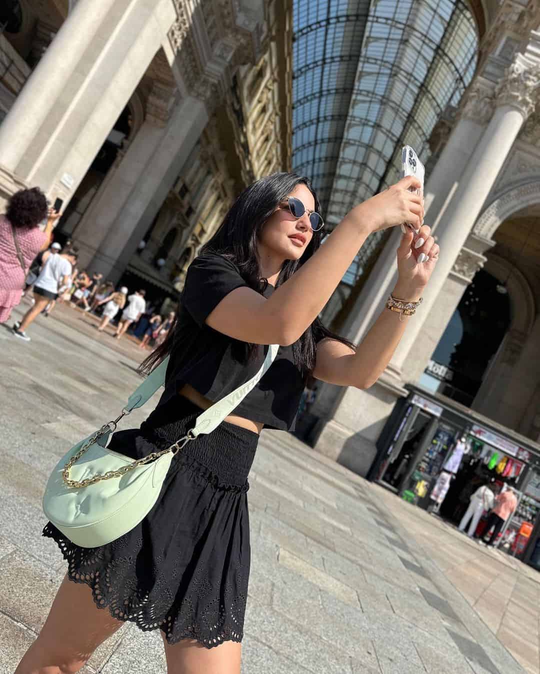 درة في ميلانو بتنورة سوداء "ميني جيب" مع فيست قصير بنفس اللون