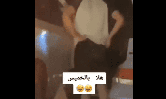 شاب يقف أمام باب السيارة ويقوم بتعديل ملابسه