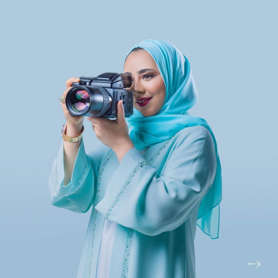 زوجة ذي يزن بن هيثم بن طارق في إحدى الاطلالات مرتدية عباءة باللون الأزرق الفاتح، حاملة في يدها كاميرا